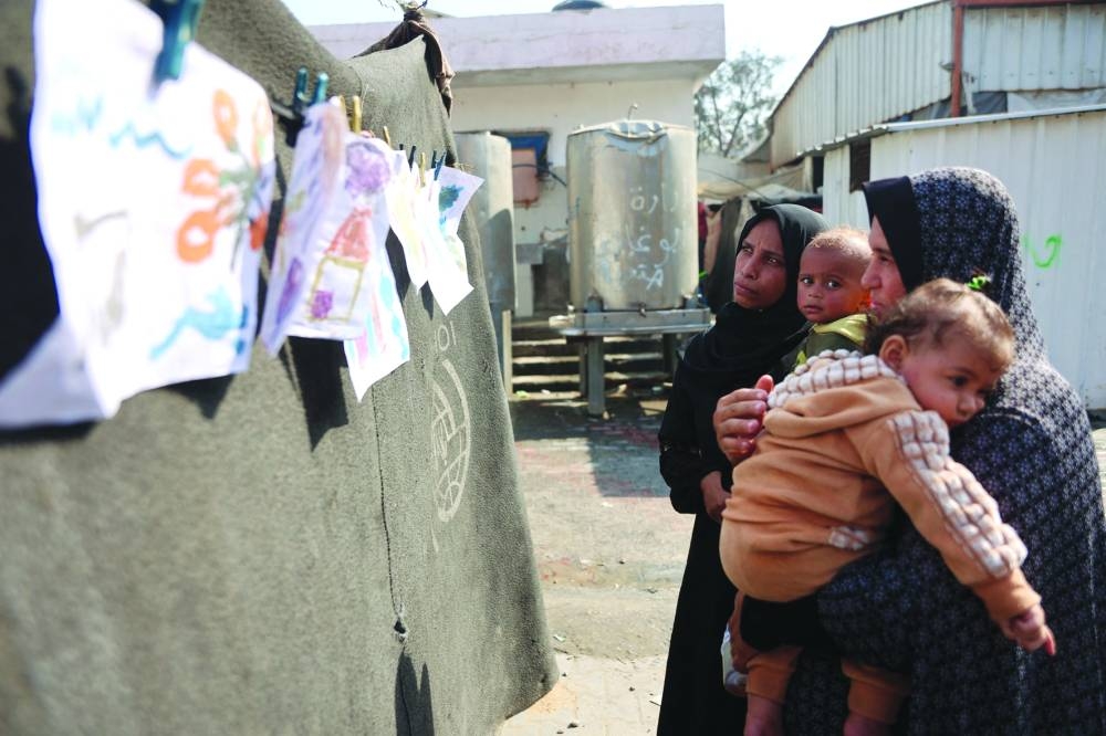 People look at an exhibition featuring a collection of drawings by children, at a school-turned-shelter in Gaza City Wednesday.