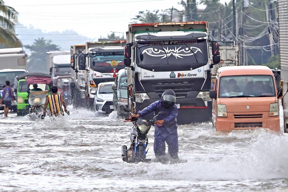 A motorist wades through a flooded highway due to heavy rain brought by Typhoon Fung-wong in Remedios T Romualdez, on the southern island of Mindanao Saturday.