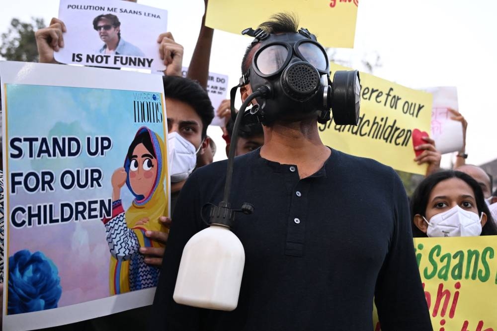 Demonstrators wearing masks hold posters during a protest demanding the government take action to reduce air pollution in New Delhi on November 9, 2025. (AFP)