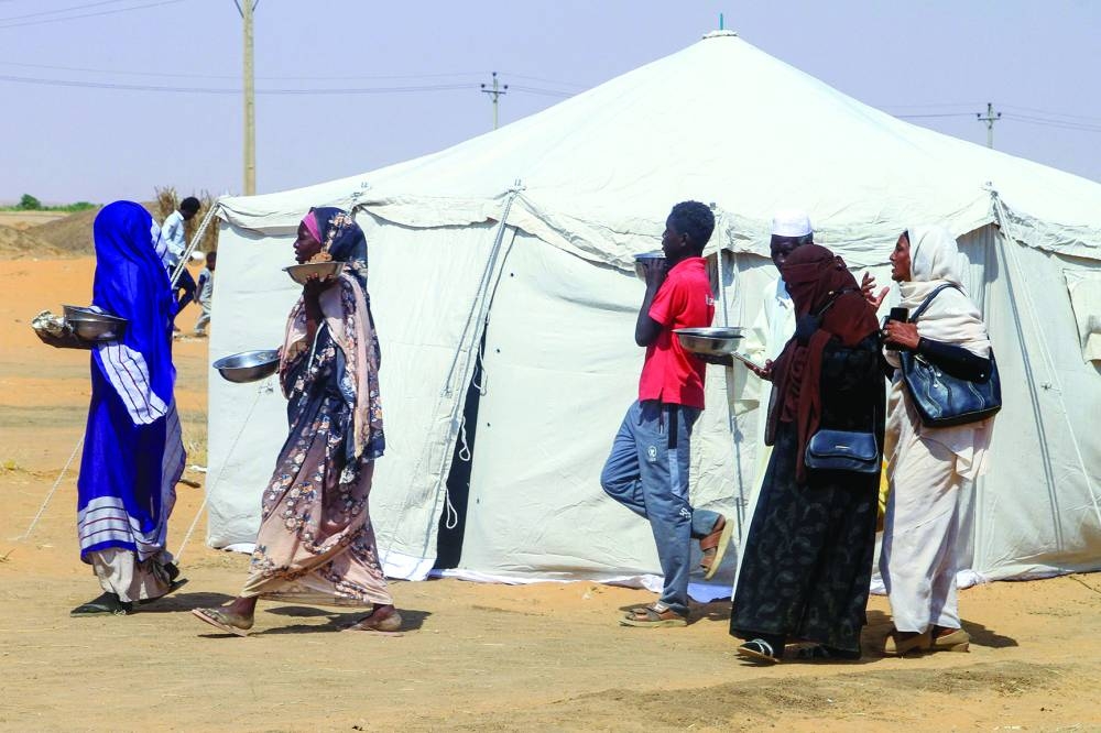 
Sudanese people who fled El-Fasher prepare a meal at a camp for the displaced in the northern town of Al-Dabba. 