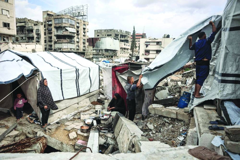 
Palestinians fix their makeshift shelter as the first winter rains fall on a displacement camp in Gaza City yesterday. The United States has called on the UN Security Council to unite and back its draft resolution aimed at bolstering the US president’s peace plan for Gaza, warning that Palestinians could otherwise suffer “grave” consequences. 