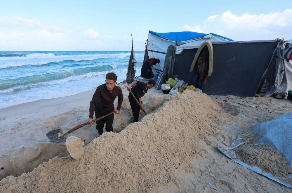 Palestinians dig to clear a path to drain water from tents, amid a ceasefire between Israel and Hamas, in Khan Younis, southern Gaza Strip, November 15, 2025. REUTERS