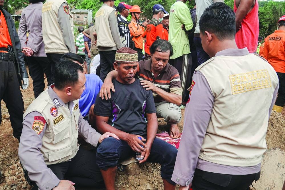 Relatives of victims react at the site of a landslide after it hit Cibeunying village in Cilacap, Central Java province, Indonesia. 