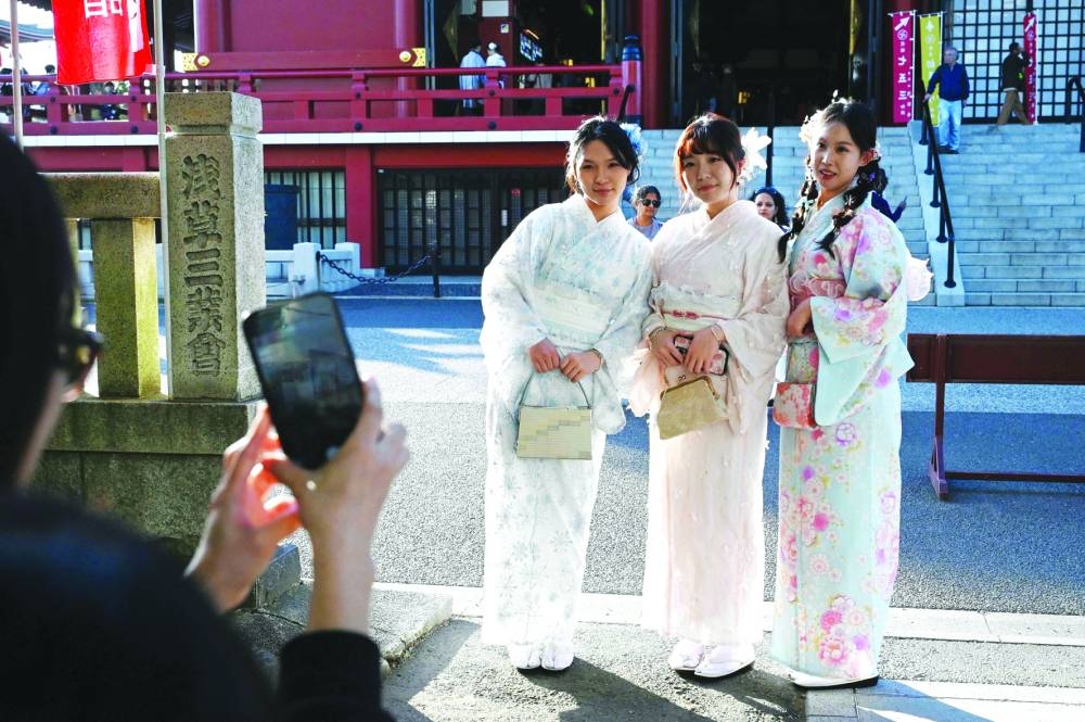 Three Chinese tourists wear kimonos as they pose for photos at the Sensoji Temple in the Asakusa district of Tokyo Saturday.