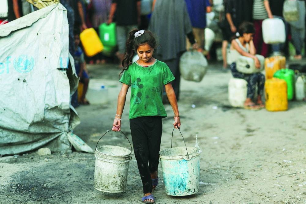 File photo shows a Palestinian girl carrying buckets of water amid shortages in Gaza City.