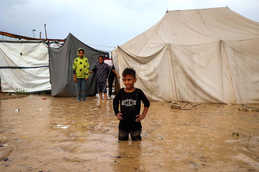 Children stand outside their tents after heavy rain flooded a makeshift camp housing displaced Palestinians in Maghazi refugee camp in the central Gaza Strip, Tuesday.
