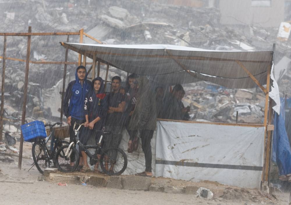 Displaced Palestinians shelter under a tent next to piles of rubble, during a rainy day in Gaza City, November 25, 2025. REUTERS