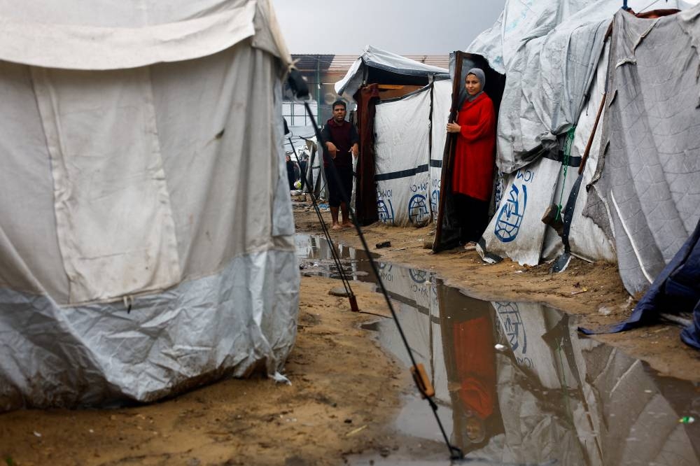 Displaced Palestinians shelter at a flooded tent camp, during a rainy day in Gaza City, November 25, 2025. REUTERS