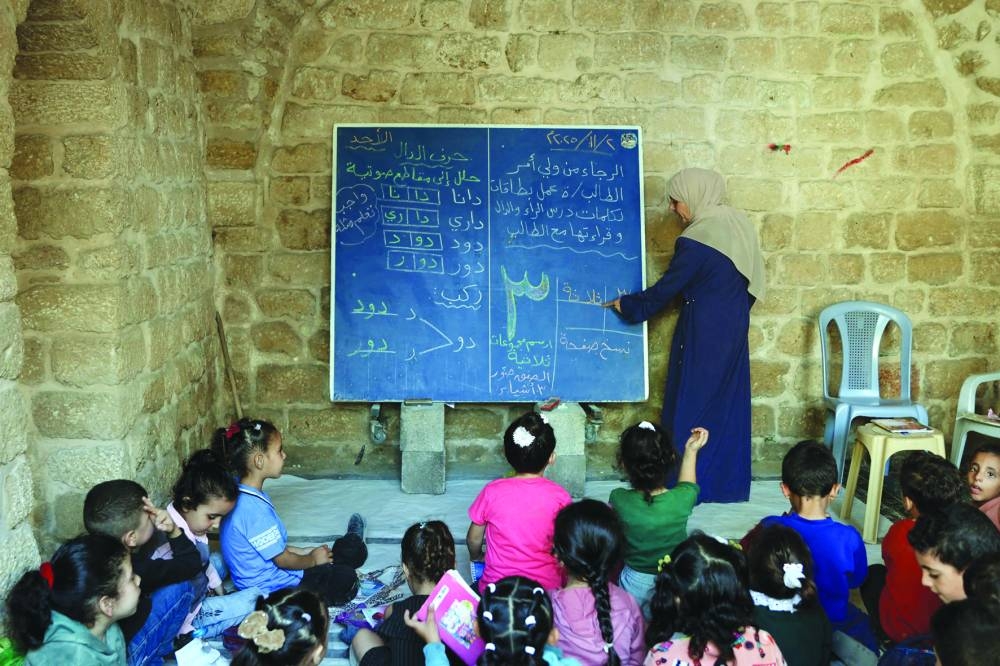 File photo shows Palestinian children attend a class in the historic "Al-Kamaliya al-Othmanya" school in Gaza City's Old Town, as part of a volunteer initiative organised by displaced teachers, in Gaza City.