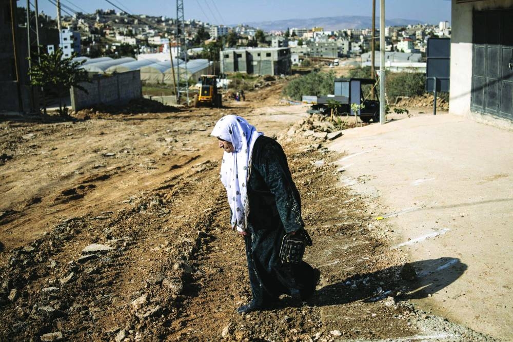 A Palestinian woman walks up a destroyed road in Tammun on November 28, 2025, during a large scale Israeli military operation in the occupied West Bank. Israel's military on November 26 launched a new operation against Palestinian armed groups in the occupied West Bank, where a local governor told AFP that Israeli forces had raided several towns. (Photo by JOHN WESSELS / AFP)