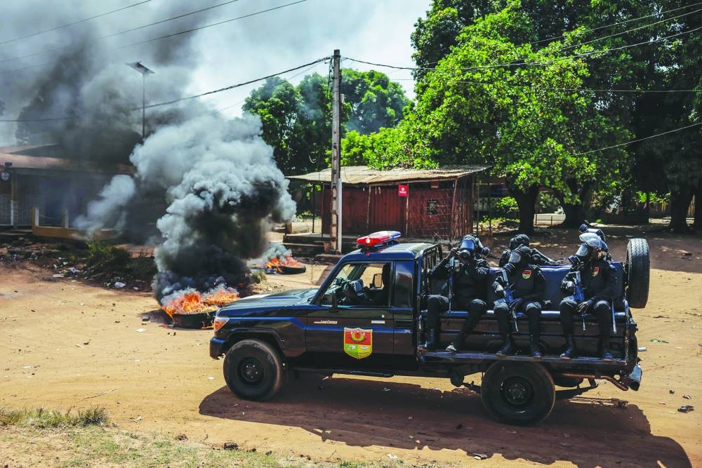 A Guinea Bissau Police patrol car speeds past burning tyres during incidents in Bissau, Saturday.