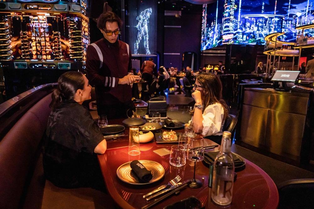 A waiter interacts with customers at Woohoo, an AI-powered restaurant in Dubai. 
