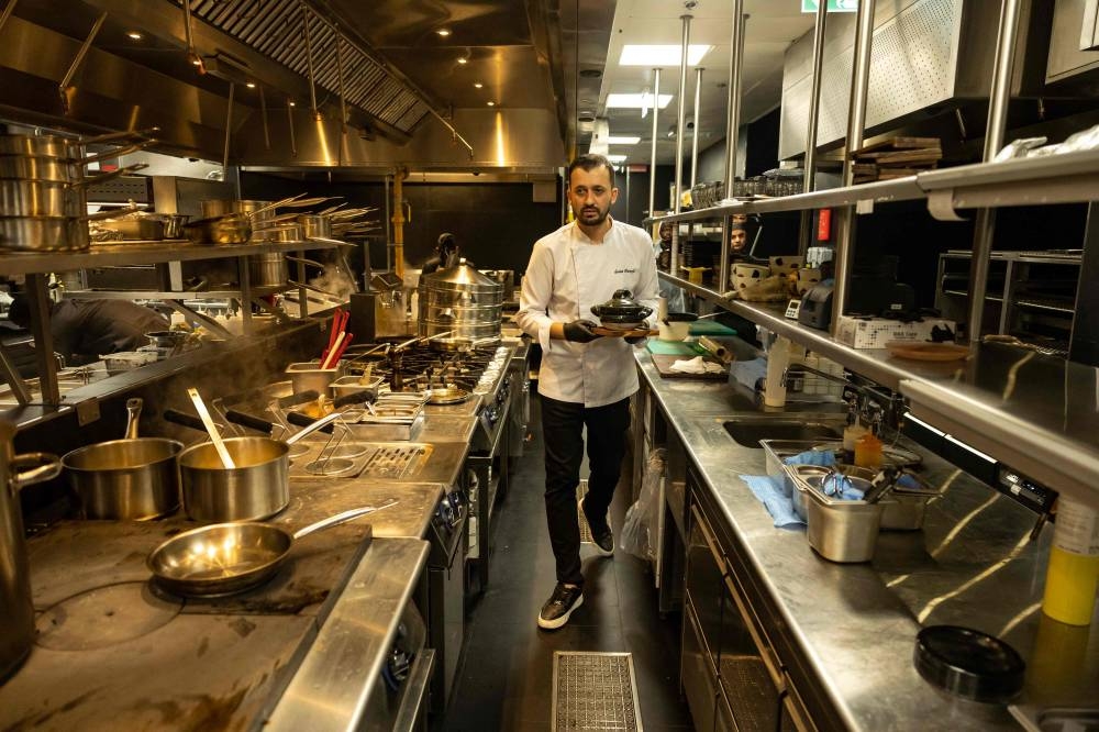 In this photograph taken on November 12, 2025, Turkish chef Serhat Karanfil works in the kitchen of Woohoo, an AI-powered restaurant in Dubai. 
