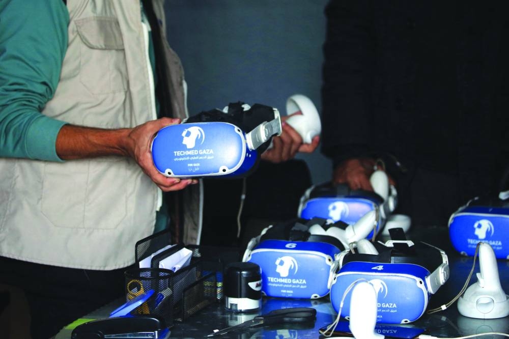A medical technology support team member demonstrates to Palestinian youth, how to use virtual reality goggles and a joystick, as part of a medical technology initiative in the city of Al-Zawayda, in the central Gaza Strip. 