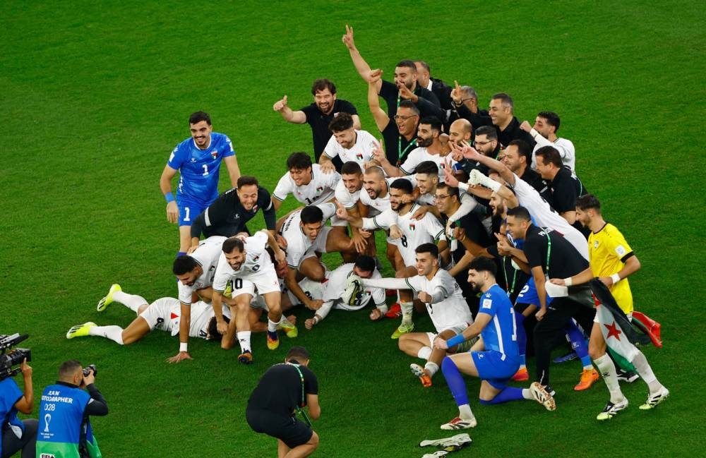 Palestine football players celebrate after qualifying for the knockout stage at the FIFA Arab Cup Qatar 2025 following their Group A match against Syria at the Education City Stadium on December 7, 2025. The matched ended in a 0-0 draw. (Reuters)
