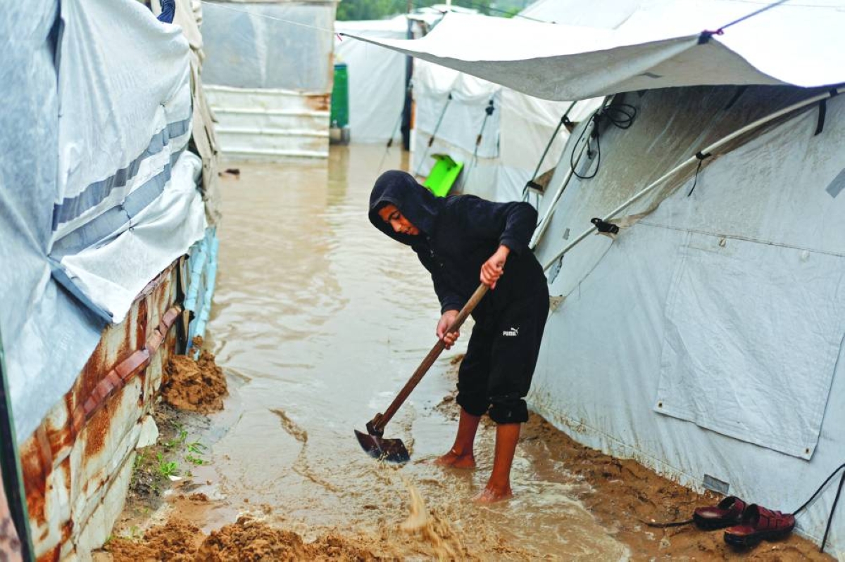 A displaced Palestinian boy uses a shovel as he stands in muddy water in a tent camp on a rainy day in Nuseirat, central Gaza Strip,yesterday.