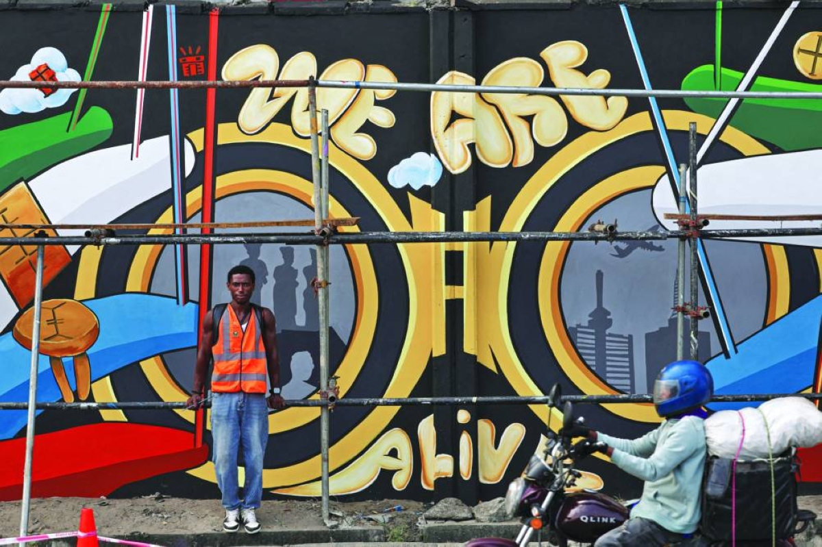 An artist poses for a photograph in front of his mural on Ozumba Mbadiwe Way, during the Lagos Street Art Festival in Victoria Island, Nigeria.