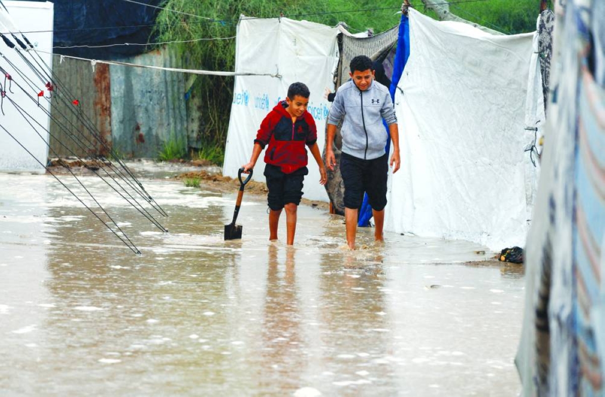 Displaced Palestinians walk through rainwater as they shelter in a flooded tent camp on a rainy day in Nuseirat, central Gaza Strip. 