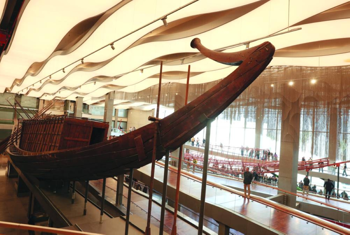 A man looks at King Khufu’s boat gem, also known as the Solar Boat, while archaeologists and workers gather around King Khufu’s second solar boat, as restored wooden planks part of the 1,650-piece structure are installed on a metal frame through Egyptian-Japanese co-operation, marking the start of preparations for public display of the second boat at the Grand Egyptian Museum, near the Giza Pyramid Complex, in Egypt, Tuesday.