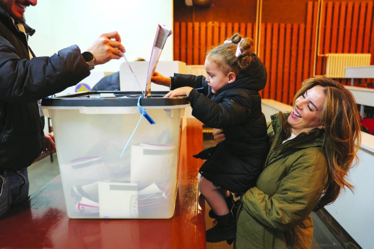 A child helps to cast a ballot at a polling station in Pristina during a snap parliamentary election. – Reuters