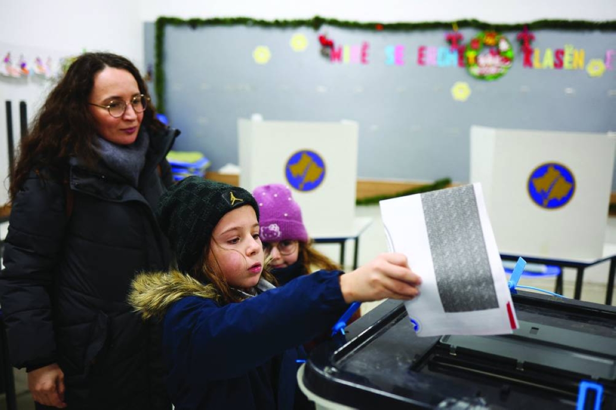 A child helps to cast a ballot at a polling station in Pristina during a snap parliamentary election. – Reuters