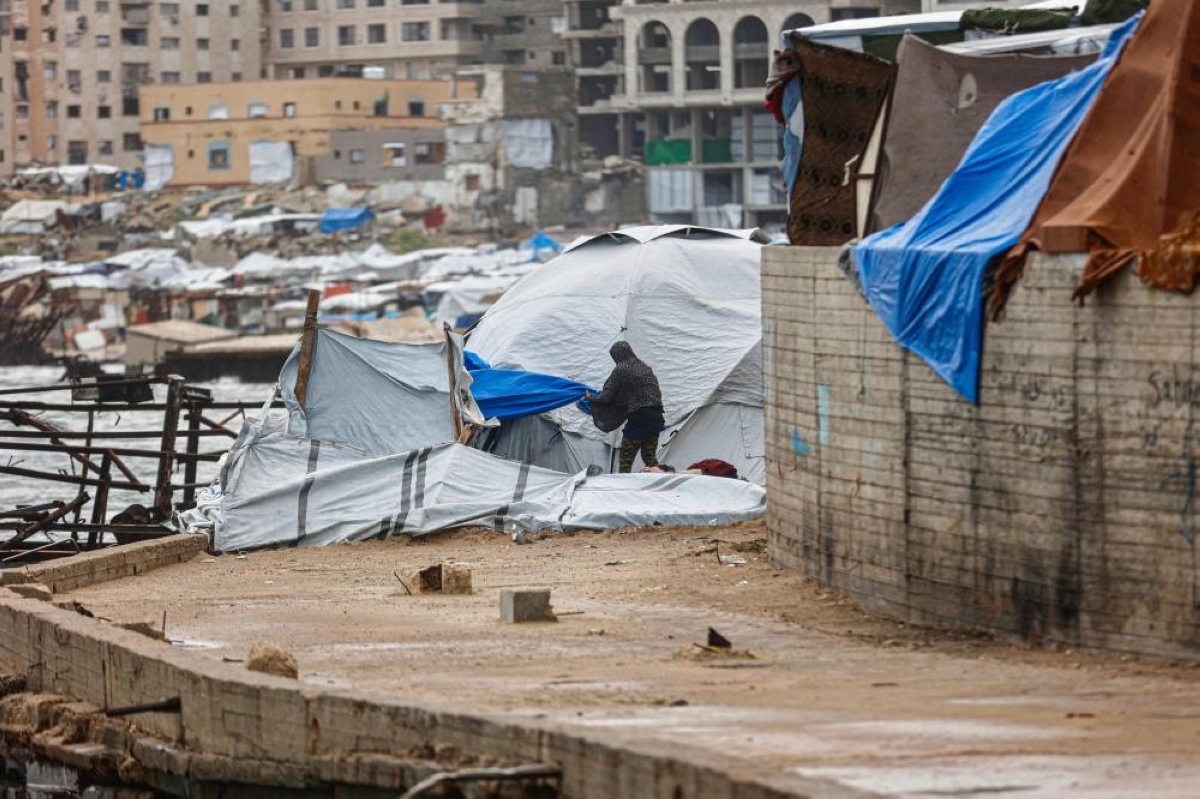 A displaced Palestinian man adjusts the canvas of the family tent shelter erected in the harbour as the region experiences rain and cold winter conditions, in Gaza City an December 28, 2025. The majority of Gaza's 2.4 million people have been displaced, often multiple times, by the war that began with Hamas's attack on southern Israel on October 7, 2023. With many displaced living in tent camps, raising serious concerns over winter. (AFP)