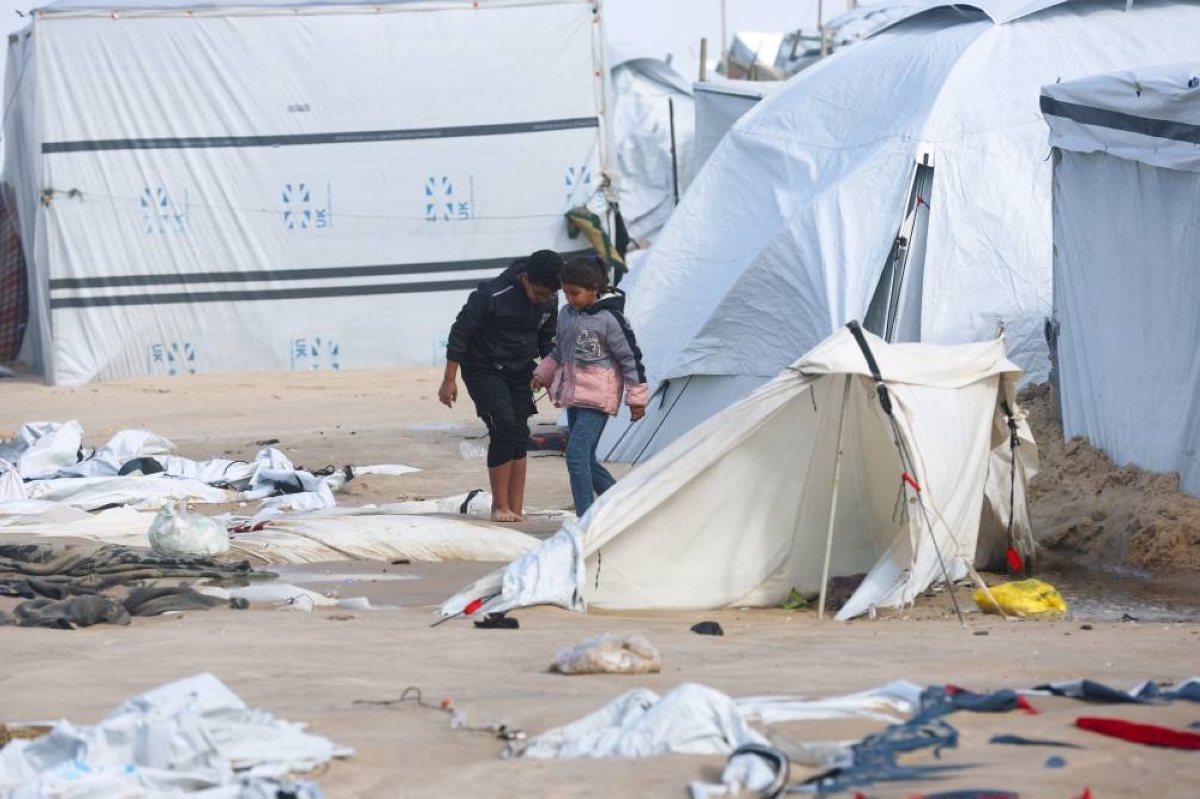 Displaced Palestinian children walk among damaged tents at a beach tent camp, after it was flooded by rising seawater during a winter storm in Khan Younis, southern Gaza Strip, December 28, 2025. REUTERS