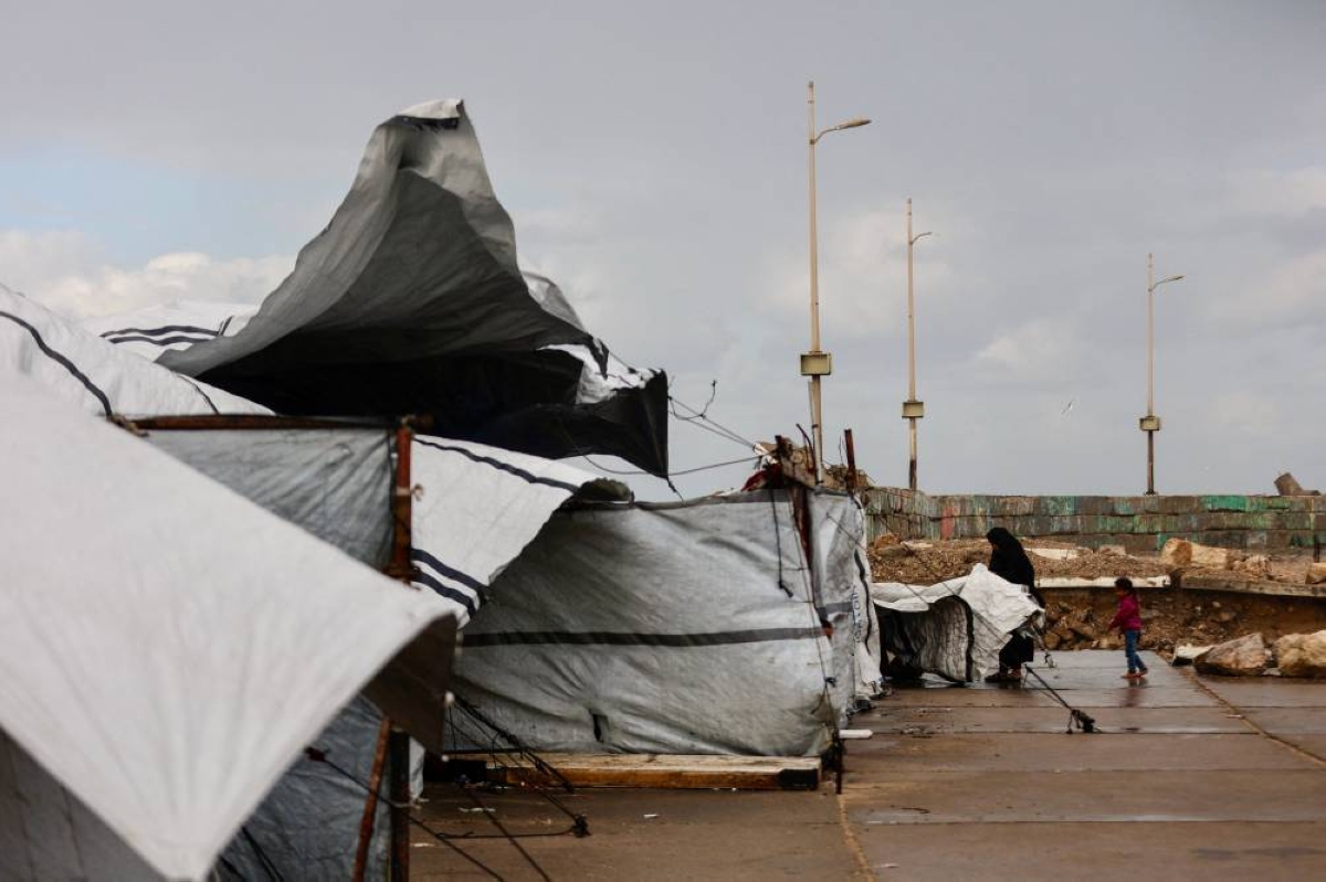 A displaced Palestinian woman adjusts the canvas of the family tent shelter as the region experiences rain and cold winter conditions, in Gaza City an December 28, 2025. The majority of Gaza's 2.4 million people have been displaced, often multiple times, by the war that began with Hamas's attack on southern Israel on October 7, 2023. With many displaced living in tent camps, raising serious concerns over winter. (AFP)