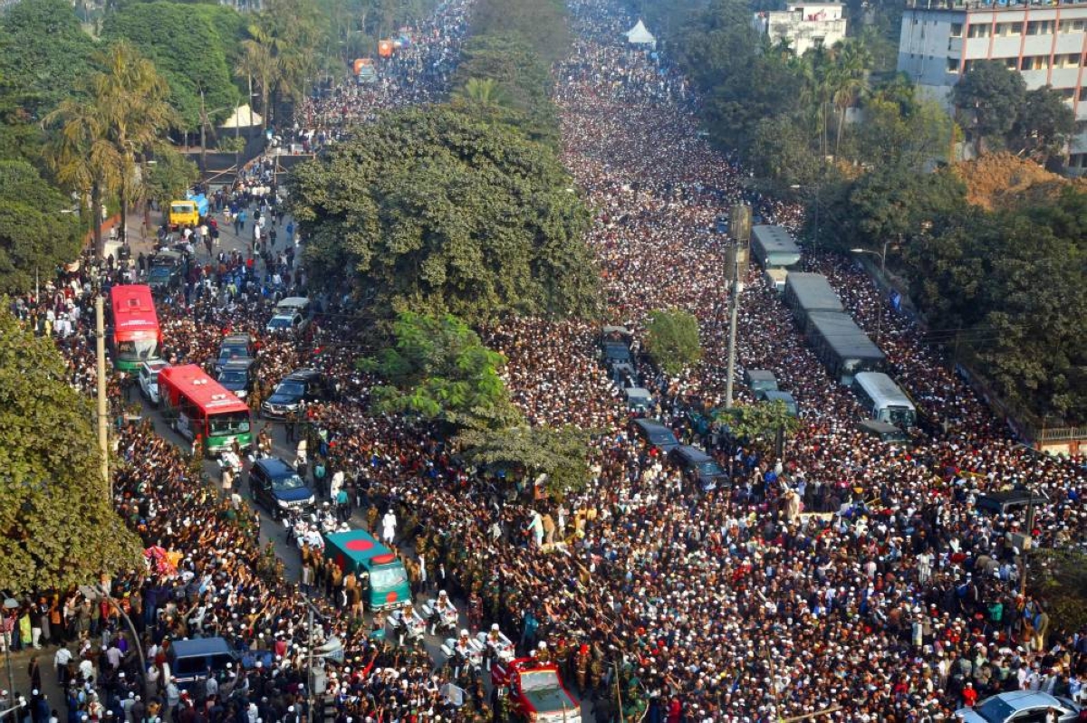 Mourners gather around a convoy carrying the mortal remains of Bangladesh's former prime minister Khaleda Zia in Dhaka on December 31, 2025, a day after her death. Bangladesh bid farewell on December 31 to Zia, the first woman to serve as prime minister in the South Asian nation of 170 million people, in a state funeral that drew vast crowds mourning a towering leader whose career defined the country's politics for decades. (Photo by Anwar HOSSAIN JOY / AFP)