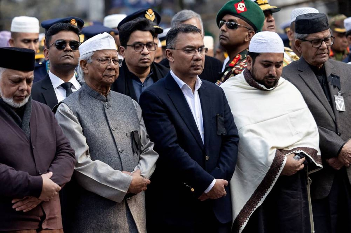 This handout photograph taken on December 31, 2025 and released by Bangladesh Nationalist Party (BNP)'s Media Cell shows BNP's acting chairman Tarique Rahman (C) standing alongside chief adviser of the country's interim government Muhammad Yunus (2L) during the burial ceremony of his mother and the nation's former prime minister Khaleda Zia a day after her death in Dhaka. Bangladesh bid farewell on December 31 to Zia, the first woman to serve as prime minister in the South Asian nation of 170 million people, in a state funeral that drew vast crowds mourning a towering leader whose career defined the country's politics for decades. (Photo by Bangladesh Nationalist Party (BNP) Media Cell / AFP) / RESTRICTED TO EDITORIAL USE - MANDATORY CREDIT "AFP PHOTO /  Bangladesh Nationalist Party (BNP) Media Cell / - / HANDOUT" - NO MARKETING NO ADVERTISING CAMPAIGNS - DISTRIBUTED AS A SERVICE TO CLIENTS