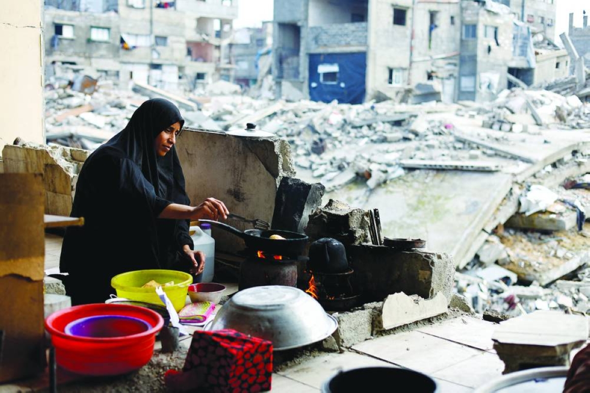A Palestinian woman cooks, with the rubble of residential buildings destroyed during the war visible in the background, in Jabalia, northern Gaza Strip, Wednesday.
