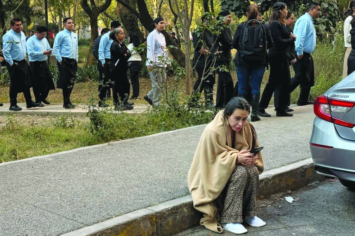 A guest uses a mobile phone on the street after evacuating a hotel alongside staff during the earthquake in Mexico City. – AFP