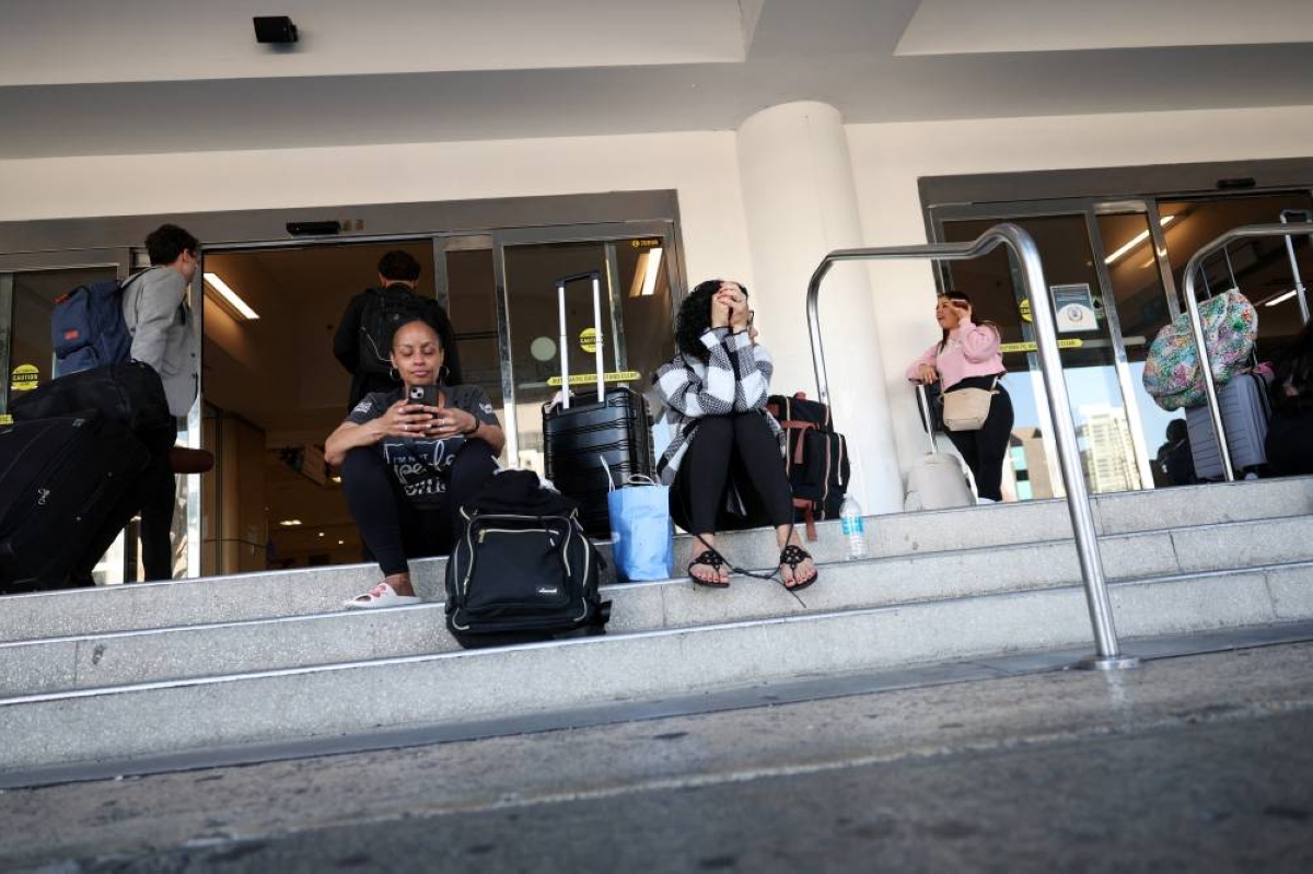 Passengers rest on the ground, after flights were delayed and cancelled when the airspace was closed due to U.S. strikes on Venezuela overnight, at Luis Munoz Marin International Airport in Carolina, near San Juan, Puerto Rico. REUTERS