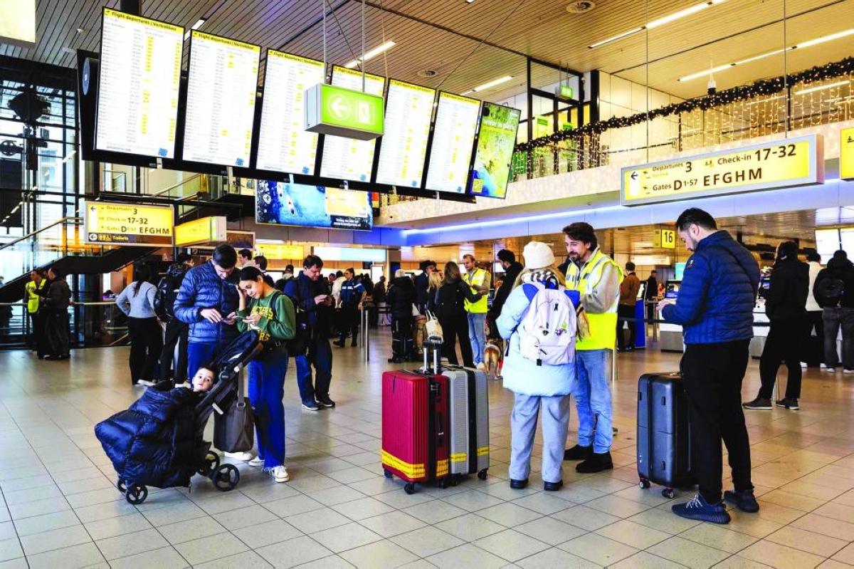 Staff members in yellow jackets assist travellers at Amsterdam Schiphol airport, where snow prompts over 700 flight cancellations Wednesday.