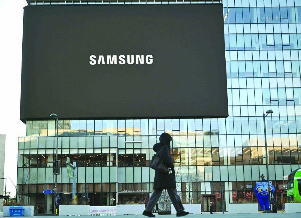 A woman walks past a large electronic screen showing the logo of Samsung Electronics at Gwanghwamun square in central Seoul. 