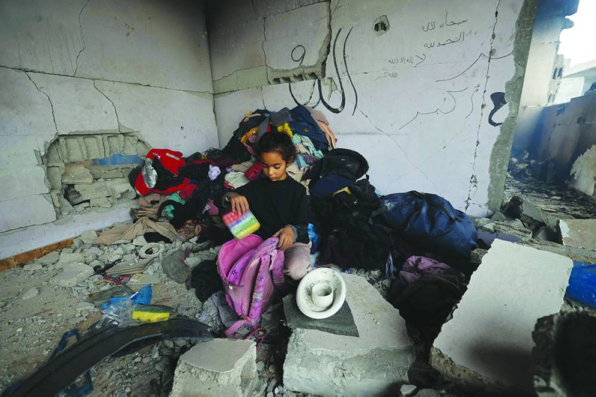 A Palestinian girl puts her salvaged belongings into a pink backpack in the Bureij camp in the central Gaza Strip on January 9, 2026 following Israeli attacks. Gaza's civil defence agency said Israeli attacks in the Palestinian territory killed at least 13 people, including five children, despite a ceasefire that has largely halted the fighting. (Photo by Eyad Baba / AFP)