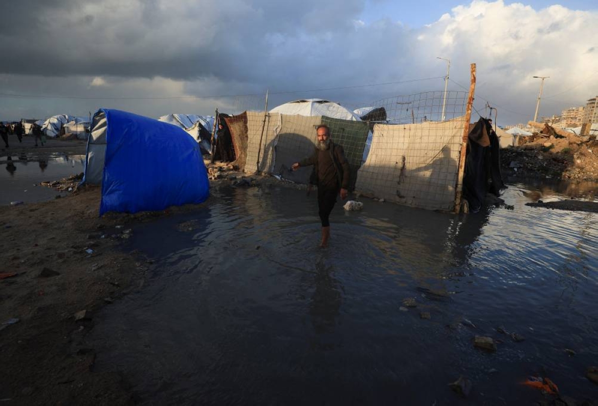 A displaced Palestinian man stands in the water, next to tents, due to a weather disturbance in Gaza City. REUTERS