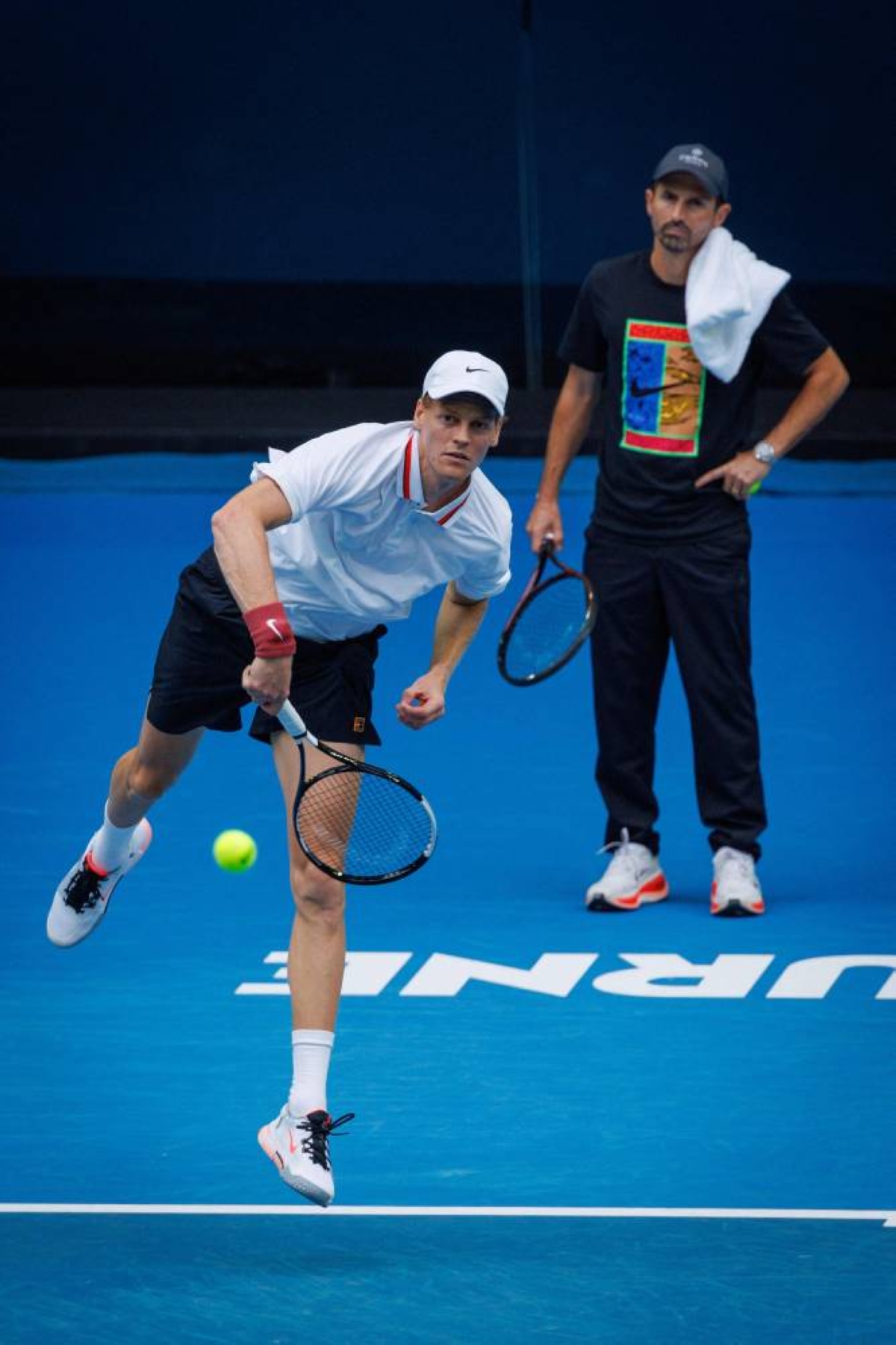 Italy’s Jannik Sinner serves under the watchful eye of coach Simone Vagnozzi (right) during a training session in Melbourne Tuesday. (AFP)
