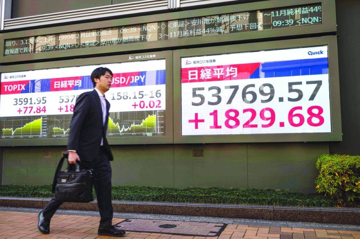 A man walks past an electronic quotation board displaying numbers of the Nikkei Stock Average on the Tokyo Stock Exchange. The Nikkei 225 closed up 3.1% to 53,549.16 points Tuesday.