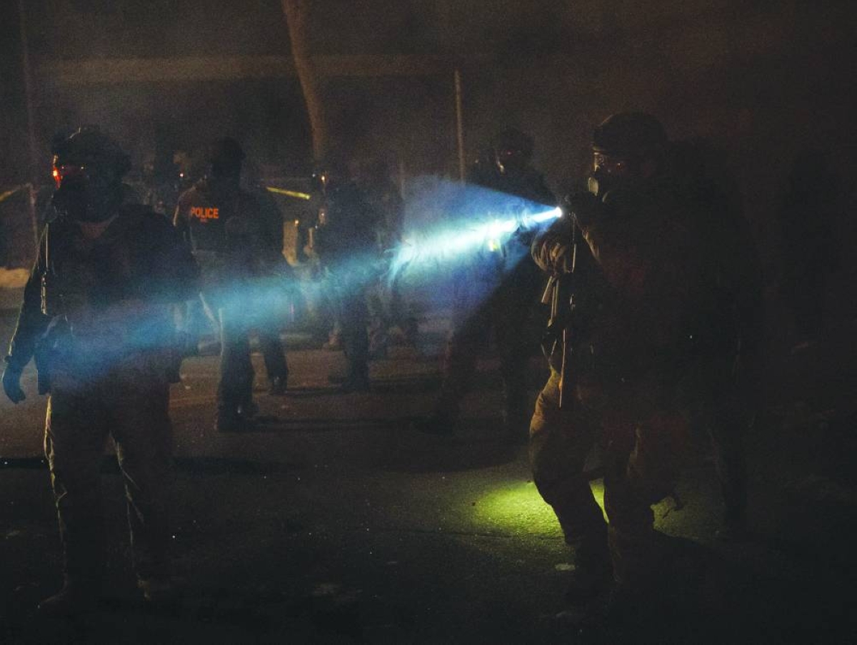 Members of federal law enforcement are seen after using tear gas on angered community members in Minneapolis. – Reuters