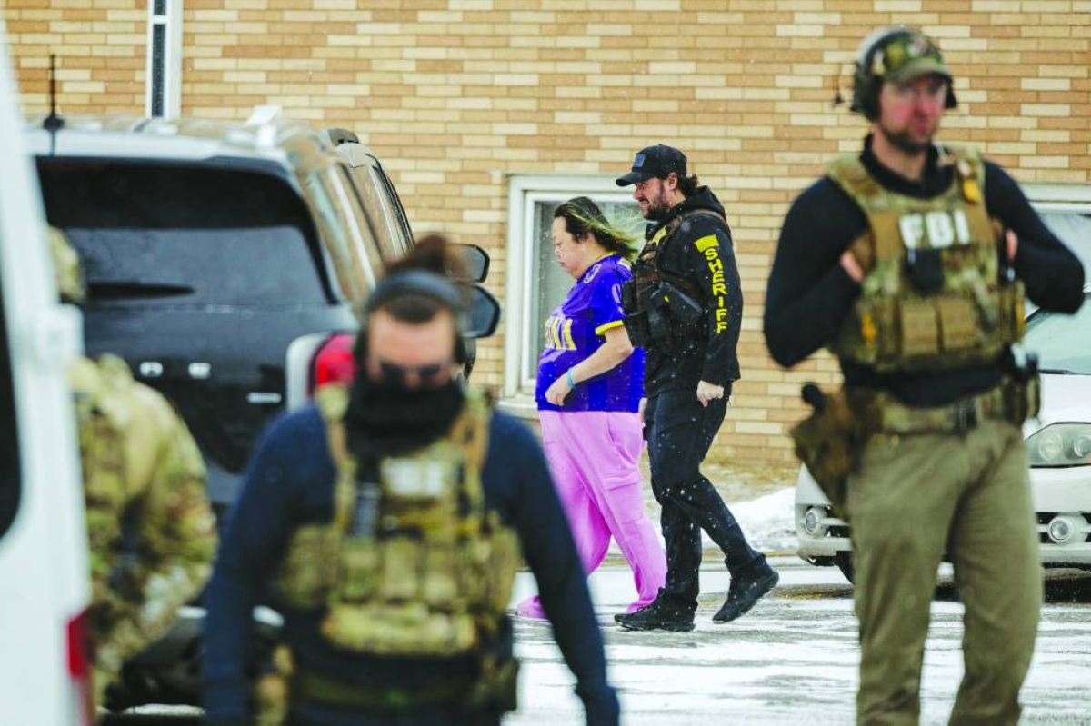 A Minnesota sheriff escorts a woman towards an unmarked vehicle after agents raided her building in St. Paul, Minnesota. AFP
