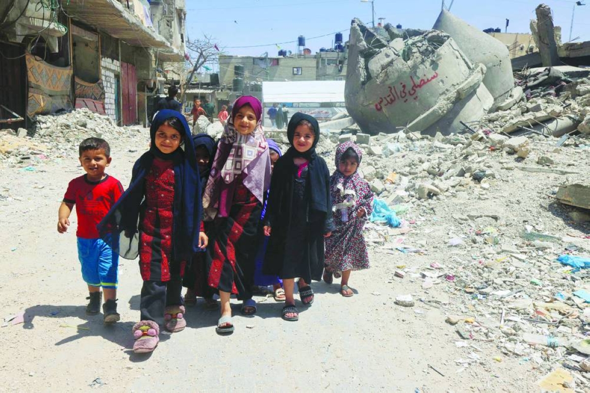 
Palestinian children walk next to the ruins of Al-Farouq Mosque, destroyed during Israeli bombardment in Rafah in the southern Gaza Strip, in a file photo. Climate change, conflict and other challenges further complicate attempts to provide access to education, particularly where it is needed most. (AFP) 