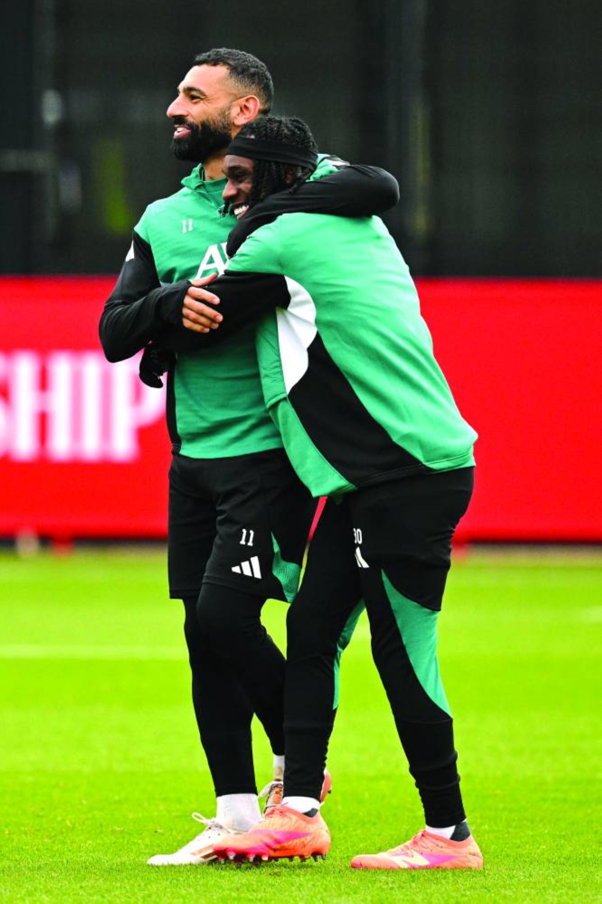 Liverpool’s Mohamed Salah laughs with teammate Jeremie Frimpong during a team training session in Kirkby Tuesday, on the eve of their UEFA Champions League match against Olympique Marseille. (AFP)