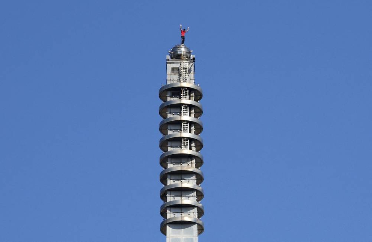 Climber Alex Honnold waves from the top of Taipei 101 after successfully free soloing the building