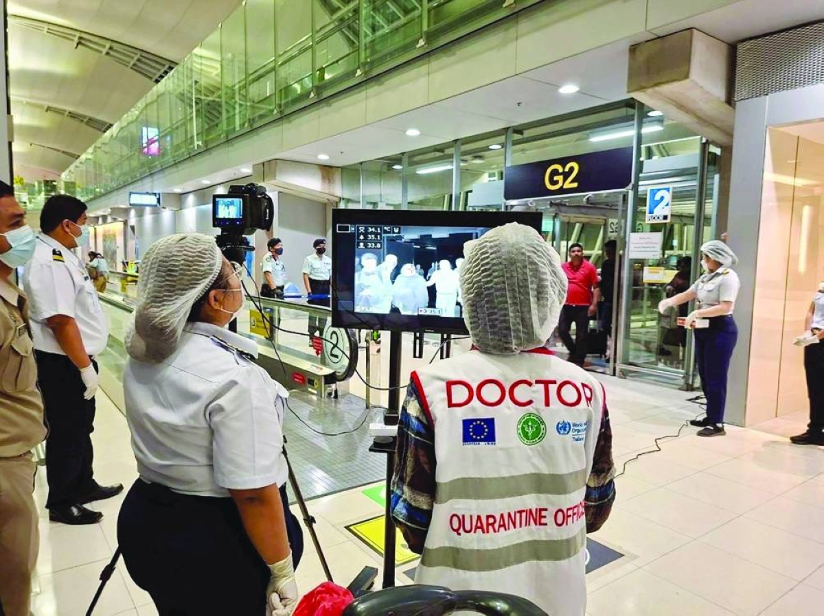 Airport health authorities wearing protective masks monitor passengers from international flights arriving at Suvarnabhumi International Airport in Bangkok, Thailand, Wednesday.