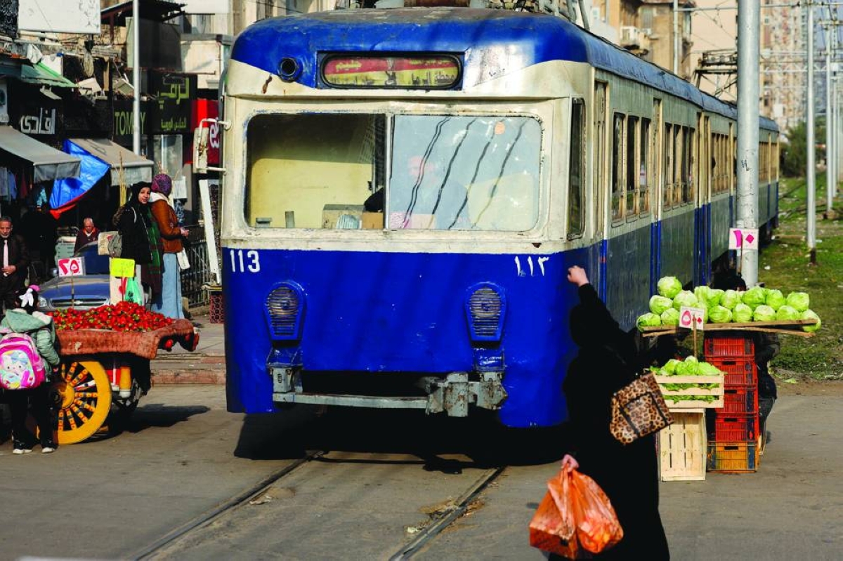 A woman gestures towards a moving tram in Alexandria. – Reuters