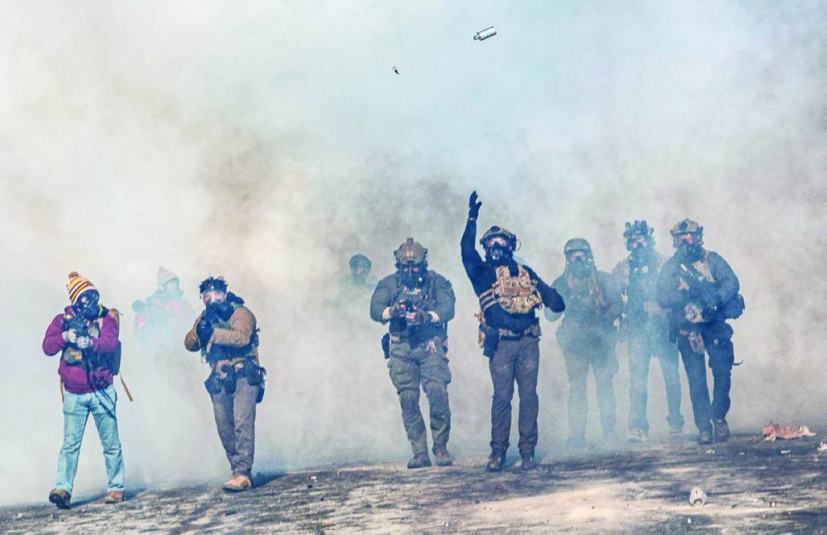 
A federal agent lobs a teargas canister towards protesters as agents advance through clouds of tear gas during clashes following the fatal shooting of a protester in Minneapolis. (AFP) 