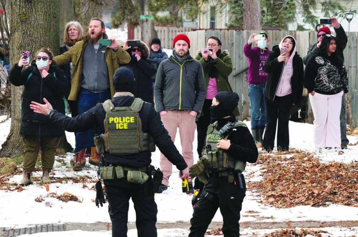 Observers film ICE agents as they hold a perimeter after one of their vehicles got a flat tyre on Penn Avenue in Minneapolis. – AFP