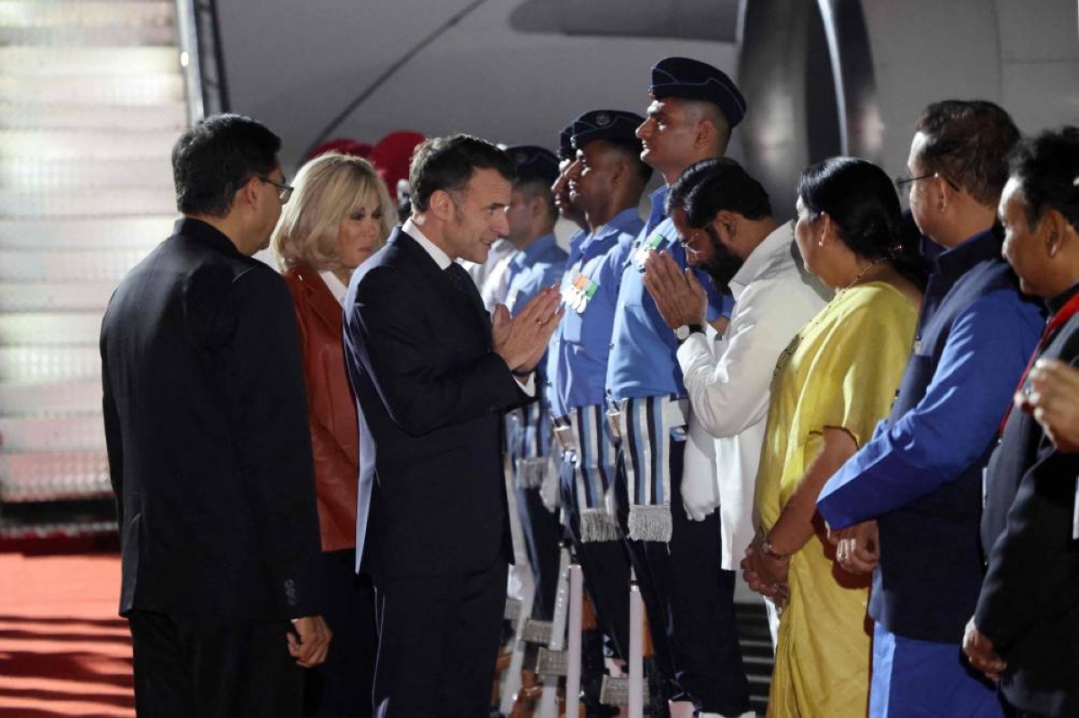 France's President Emmanuel Macron (C-R) and his wife Brigitte Macron (C) are welcomed by India's officials upon their arrival in Mumbai on February 17, 2026. The French president begins a three-day official visit to Mumbai and then New Delhi, his fourth trip to India since 2018, which will be punctuated by a series of events alongside the Indian Prime Minister. (Photo by Ludovic MARIN / AFP)