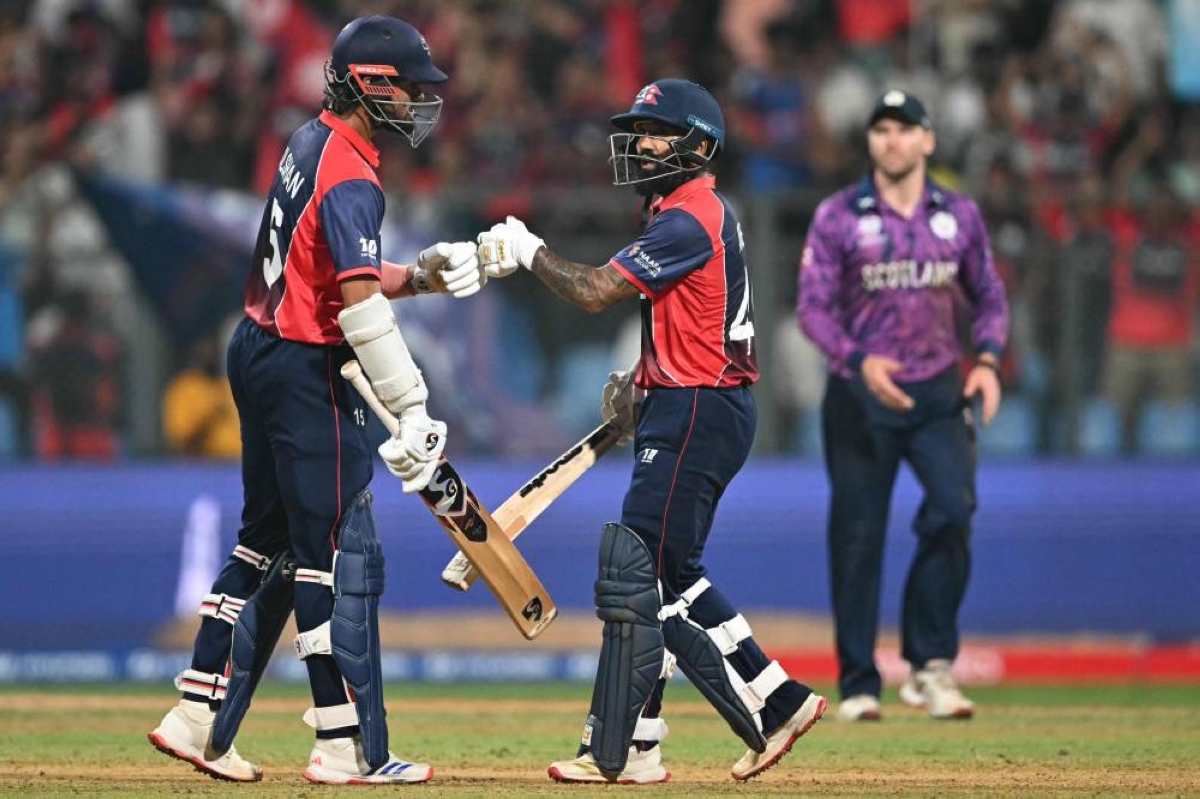 Nepal's Gulsan Jha (left) and Dipendra Singh Airee (centre) bump fists during the 2026 ICC T20 World Cup group stage match against Scotland in Mumbai on February 17, 2026. (AFP)